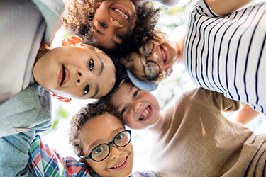 A group of children posing together with smiles, some looking directly at the camera while others are slightly turned away.