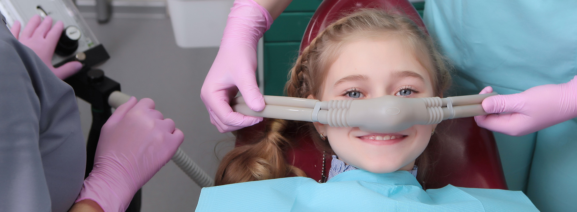 A young girl receiving dental care in a dental office, with medical professionals attending to her.